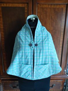 a women's blue and white jacket hanging on a wooden cabinet next to a black dress