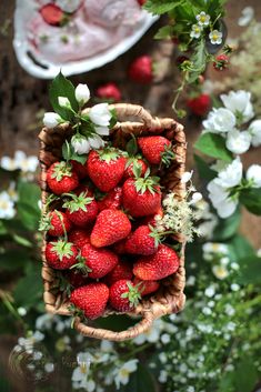 a basket full of strawberries sitting on top of a table next to white flowers