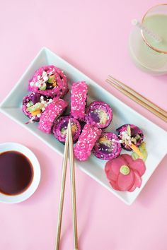 a plate with pink donuts and chopsticks next to a cup of coffee