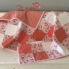 a pink and white quilted blanket sitting on top of a table