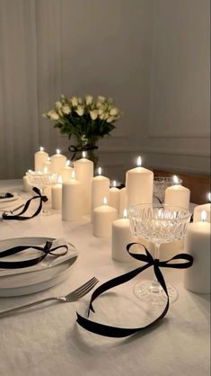 a table topped with white candles and plates