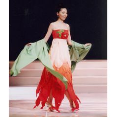 a woman is walking down the runway in a colorful dress