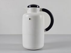 a white and black coffee pot sitting on top of a table