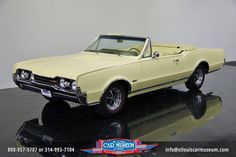 an old yellow car is on display in a showroom