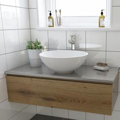 a white bowl sink sitting on top of a wooden counter next to a bathroom window