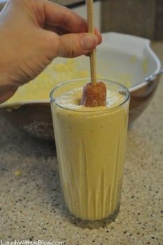 a hand holding a wooden stick over a drink