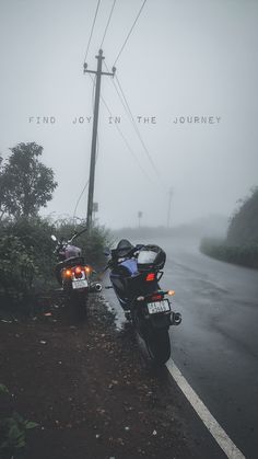 two motorcycles parked next to each other on the side of a road in the fog