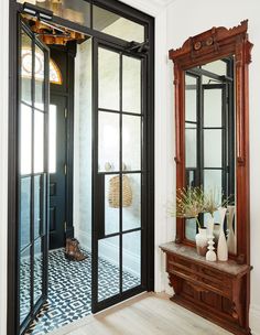 an entryway with black and white tile flooring and wooden framed mirror on the wall