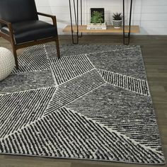 a black and white rug in a living room next to a chair with a plant on it