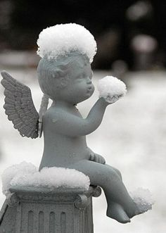 black and white photograph of an angel sitting on top of a trash can in the snow