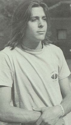 black and white photograph of a young man with long hair wearing a t - shirt