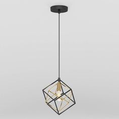 a black and gold geometric light fixture hanging from a gray ceiling with a white wall in the background