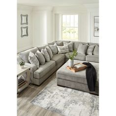 a living room with a large sectional couch and coffee table in the corner, along with a rug on the floor