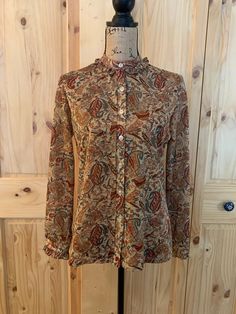 "1 front buttons sheer Aladdin blouse  Paisley multi color pattern, brown, tan and maroon  7 button closure with button cuffs  Neck and cuffs are ruffled with  Sleeve length 24\", blouse length 26\" Chart size medium  1970 1 solid tan turtleneck  Polyester  11\" back zipper closure  Sleeve length 23\", blouse length 24\" Chart size small  1960 Both blouses are in excellent vintage condition" Classic Brown Blouse With Button Cuffs, Fall Paisley Print Button-up Blouse, Casual Brown Blouse With Button Cuffs, Fitted Button-up Paisley Print Blouse, Fall Paisley Print Button-up Top, Brown Floral Print Long Sleeve Blouse, Patterned Button-up Blouse With Button Closure, Casual Fall Blouse With Covered Buttons, Classic Floral Print Top For Fall