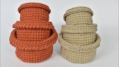 three crocheted baskets sitting next to each other on a white surface, one is orange and the other is beige