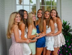 a group of young women standing next to each other in front of a white building