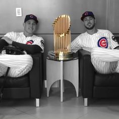 two baseball players sitting in chairs holding trophies