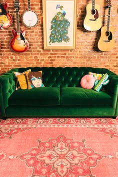 a green couch sitting in front of a brick wall with guitars hanging on the wall