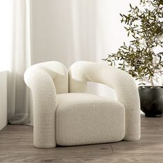 a white chair sitting on top of a wooden floor next to a potted plant