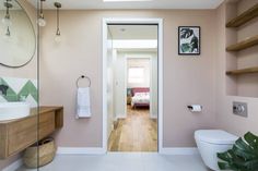 a bathroom with pink walls and wooden shelves