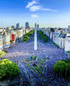 a large group of people gathered in the middle of a city with a obelisk