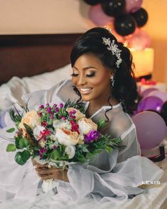 a woman sitting on top of a bed holding a bouquet