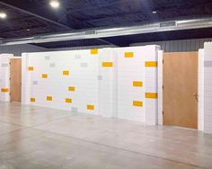 an empty room with yellow and white tiles on the walls, and three doors in the center