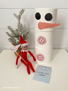 an elf is next to a roll of toilet paper with a snowman on it