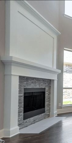 an empty living room with a fireplace and large windows