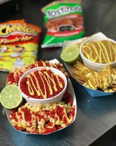 three bowls filled with food sitting on top of a table next to two bags of chips