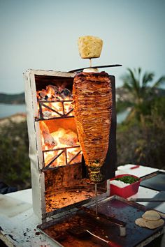 an open oven with food cooking in it on top of a table next to a body of water