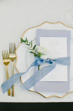 a place setting with silverware and blue ribbon