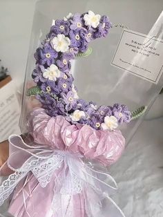 a purple and white flower arrangement in a clear case with ribbon on the bottom that says'i love you '