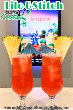 two cocktails with pineapple garnish sit on a table in front of a television