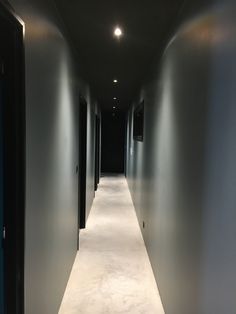 an empty hallway with white carpet and black doors