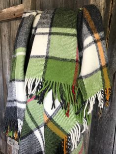 a green and black plaid blanket hanging on a wooden wall