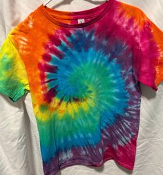 a colorful tie - dyed shirt hanging on a clothes line with white sheets in the background