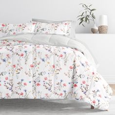 a bed with white and pink flowers on the comforter is shown in this image