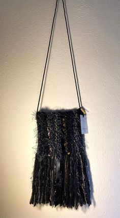 "This knitted purse is 100% handmade and features a luxurious Chinese silk lining with French brocade trim and a handy internal pocket. It is super soft and has a zipper for secure closure. It can be worn crossbody or over the shoulder as it is easily shortened to a preferred length by adding a simple knot at the apex of the strap. The body of the purse is lined with colored, hair-like strands that flow in the breeze and it features long tassels at the bottom that sway with your movement.  Measurements: Body: 8.5\" wide, 7.5\" height  Height from top of body to bottom of fringe: 15\" Inside pocket: 4\" wide, 3.5\" height  Strap: 48\" As these items are handmade, all measurements are approximate and there may be subtle variation. Please note: the colors of some pictures may vary slightly on Elegant Handwoven Crossbody Shoulder Bag, Woven Pouch Shoulder Bag For Evening, Chic Handwoven Shoulder Bag For Evening, Chic Handwoven Evening Shoulder Bag, Chic Evening Handwoven Shoulder Bag, Luxury Crochet Pouch Bag For Evening, Black Handwoven Shoulder Bag For Evening, Black Handwoven Evening Shoulder Bag, Evening Black Handwoven Shoulder Bag