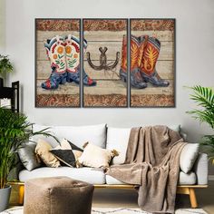 three paintings on the wall of a living room, one with cowboy boots and an umbrella