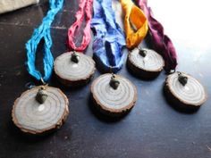 several pieces of wood are sitting on the table with ribbons around them and some beads hanging from it