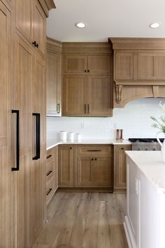 a large kitchen with wooden cabinets and white counter tops, along with hardwood flooring