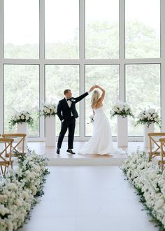 a bride and groom dancing in front of large windows at the end of their wedding ceremony