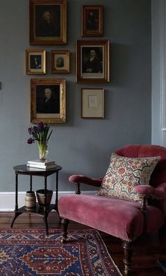 a living room filled with furniture and pictures on the wall behind a chair next to a table