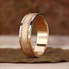 a wedding ring with two rows of diamonds on the inside and outside, sitting on top of a piece of wood