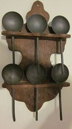 a wooden shelf with metal balls and spoons hanging from it's sides on the wall