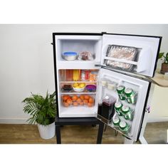 an open refrigerator with its door wide open and food in the freezer compartment, next to a potted plant