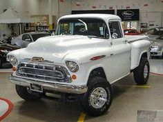 an old white pickup truck parked in a showroom