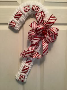 a red and white christmas wreath hanging on the front door with candy canes attached to it