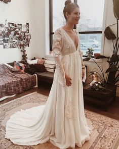 a woman in a white wedding dress standing on a rug next to a large window